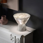 Cropped closer on the shade, the Clérachic alabaster lamp sits on the same white fireplace mantel as before.