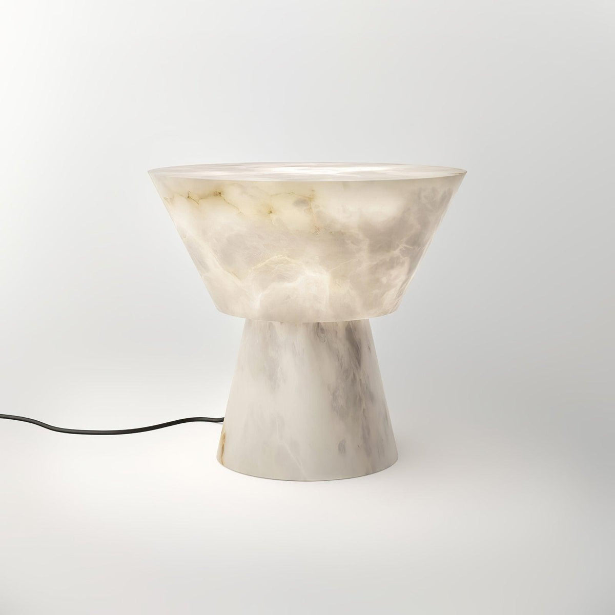 A black power cord trails from the Clérachic alabaster lamp's base across the white studio background.
