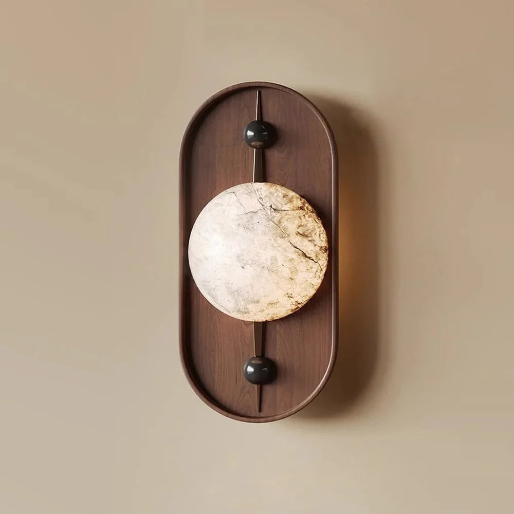 The same wall light on a warm beige wall, its alabaster disc showing amber and grey veining.