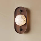 The same wall light on a warm beige wall, its alabaster disc showing amber and grey veining.