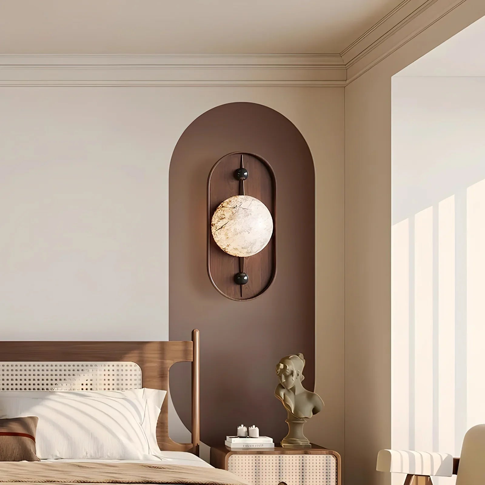 The wall light lit on a brown arched panel in a bedroom, above a rattan bed and a bust sculpture.