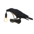 A closer view shows the textured black resin feathers of this Clérachic bird lamp, its bulb glowing warm at the beak.