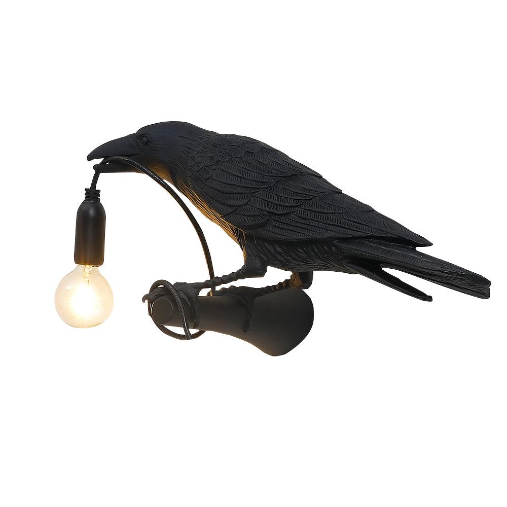 A closer view shows the textured black resin feathers of this Clérachic bird lamp, its bulb glowing warm at the beak.