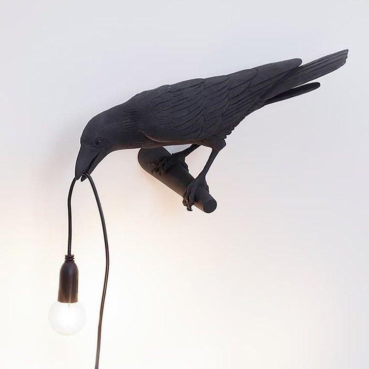 This black resin Clérachic bird lamp hangs its bulb low against a plain white ground, cord trailing to the base.