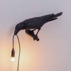 Set against a warm cream gradient, this black Clérachic bird lamp spreads its wings with the bulb glowing below.