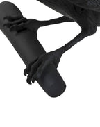Close view of the clawed feet gripping the black cylindrical wall mount on this Clérachic bird lamp.