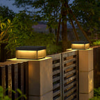 Black metal post light glowing warmly in a landscaped garden