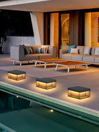 Black outdoor post light glowing along a garden pathway