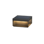 Black outdoor post light glowing softly among garden plants