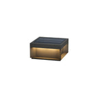 Boxy black post light glowing along a garden pathway at night