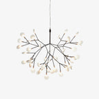 Black branch LED chandelier glowing warmly in a living room