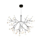 Black branch chandelier with firefly-like glowing tips over a table
