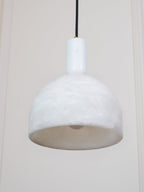 A tight crop from below shows the pale interior and rim of this Clérachic pendant, its brass fitting just visible above the unlit shade.