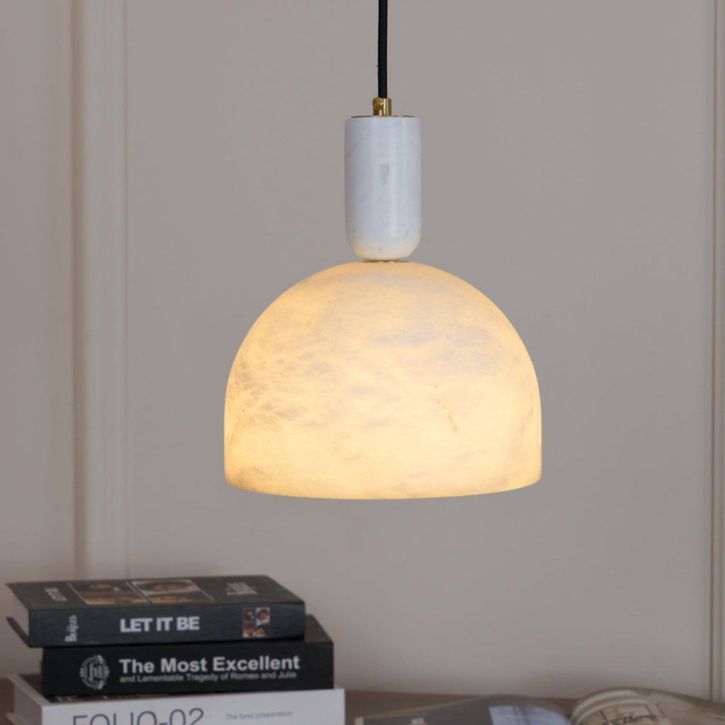 A second close view of the Clérachic pendant over the same book-stacked sideboard, framed from a slightly different angle.