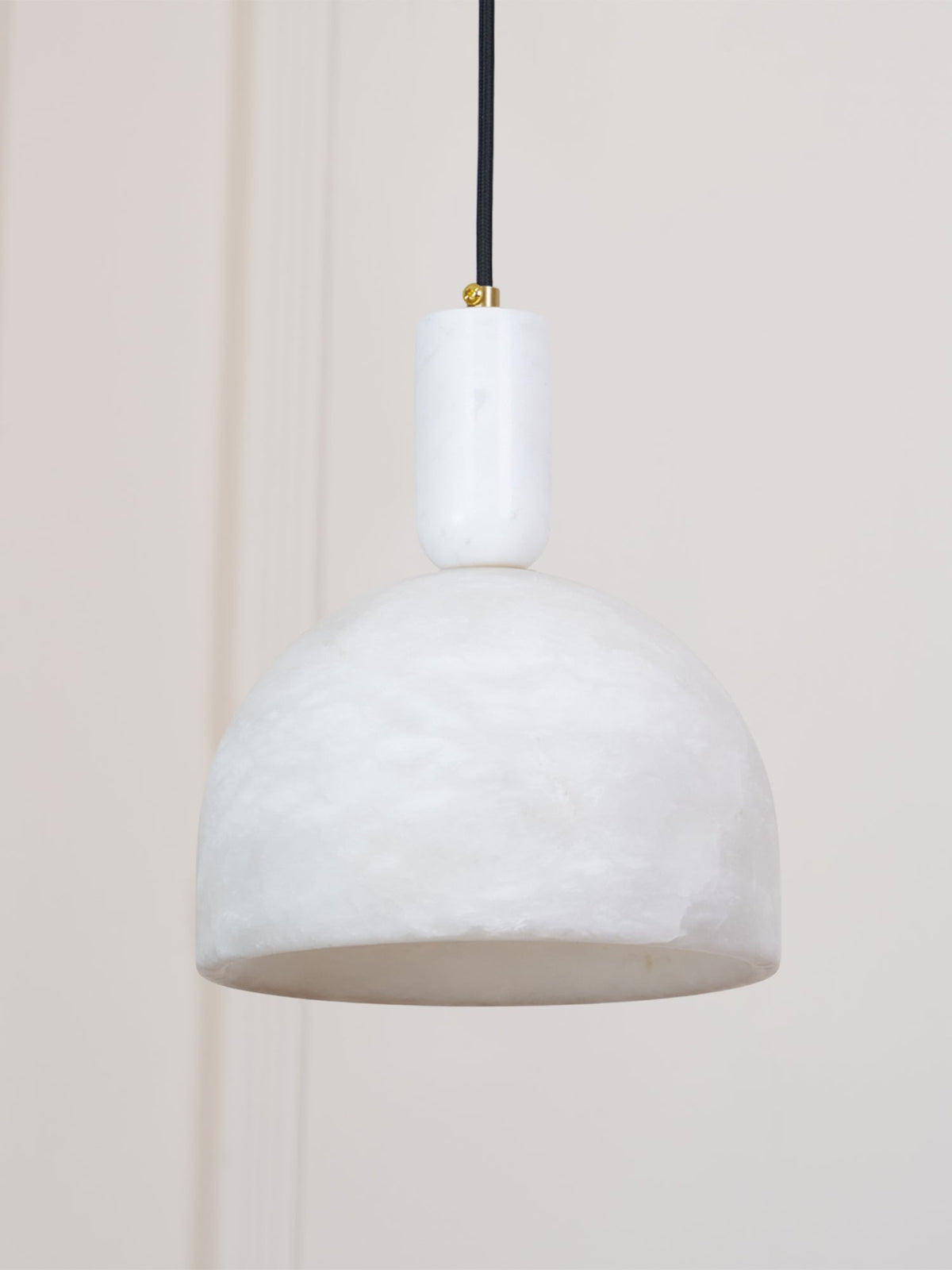 The same wall-side setting shows this Clérachic alabaster dome pendant unlit, its pale stone catching the room's daylight.