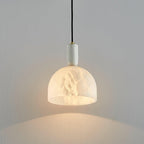 Clérachic alabaster pendant light on a plain wall, shown at a slight downward angle with the dome fully lit.