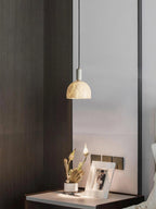 Clérachic alabaster pendant light glowing above a bedside table set with dried flowers and a small framed photograph.