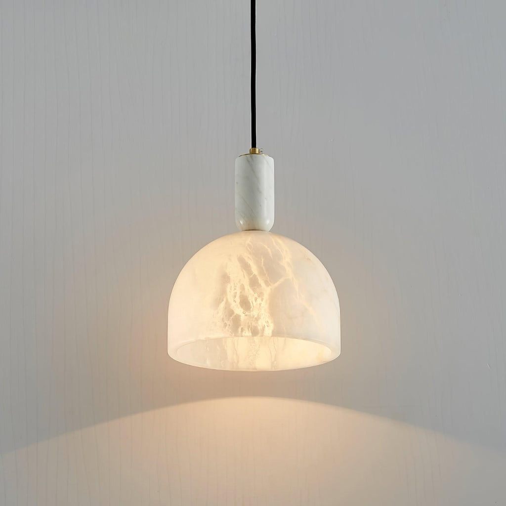 Clérachic alabaster pendant light against a plain grey wall, its dome shade glowing softly with no other furniture in view.