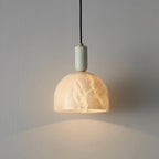 A closer wall shot of the Clérachic alabaster pendant light, the dome shade filling more of the frame against the same grey wall.