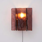 Wine-red glass wall sconce with warm brass body glowing softly