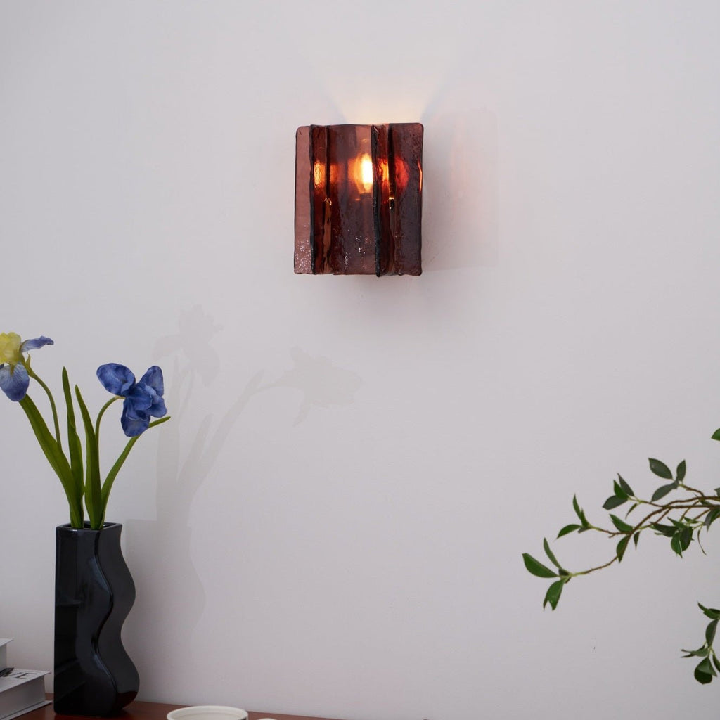 Brass wall sconce casting refracted geometric patterns in a bedroom