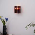 Brass wall sconce casting refracted geometric patterns in a bedroom