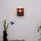 Brass wall sconce with wine red glass lit in a living room