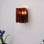 Brass wall sconce glowing warmly with wine red glass shade