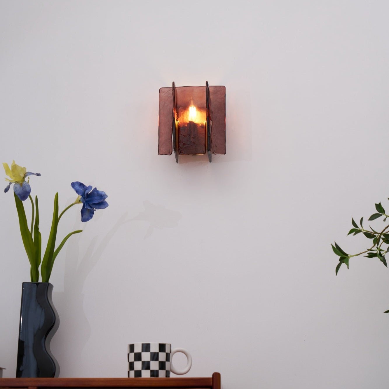 Brass wall sconce glowing with warm light and geometric shadows