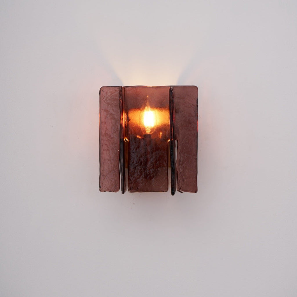 Gold brass wall sconce with wine red glass mounted on a wall