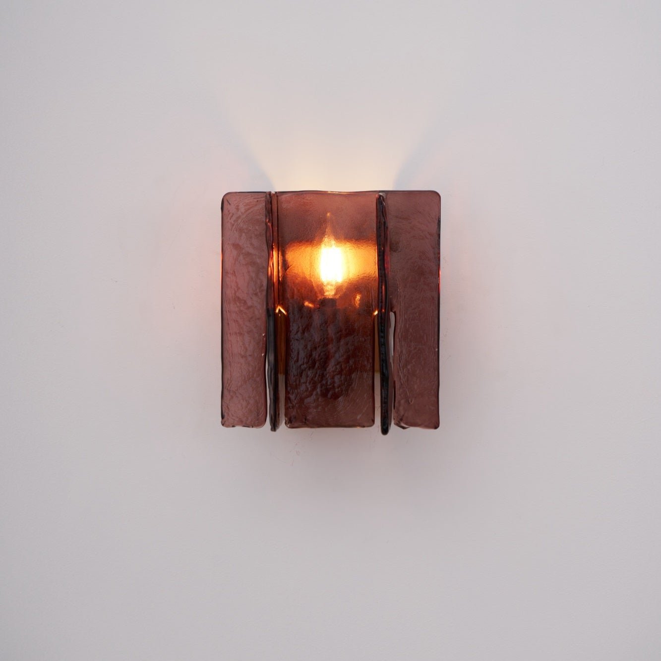 Gold brass wall sconce with wine red glass mounted on a wall