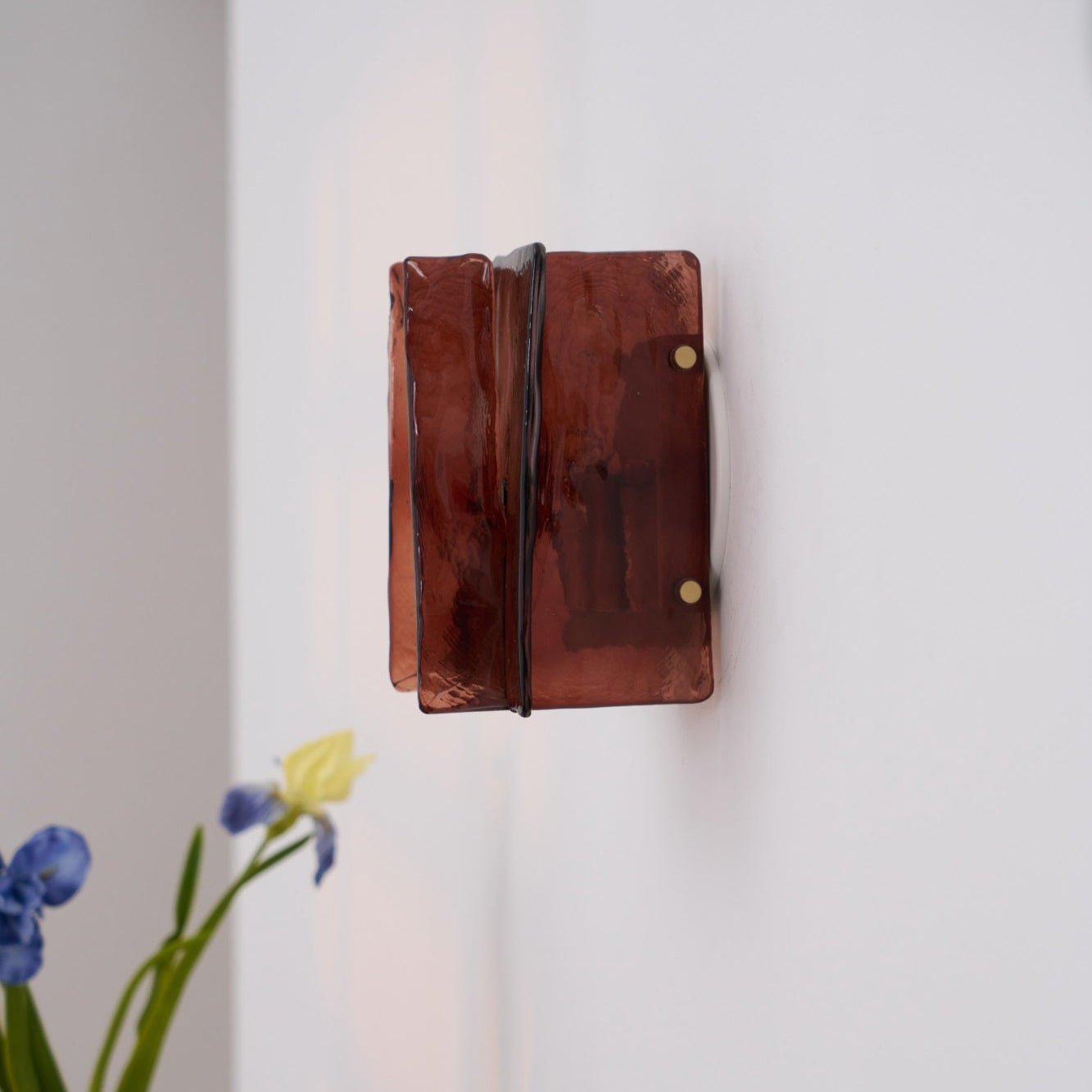 Brass wall sconce glowing against a dark interior wall