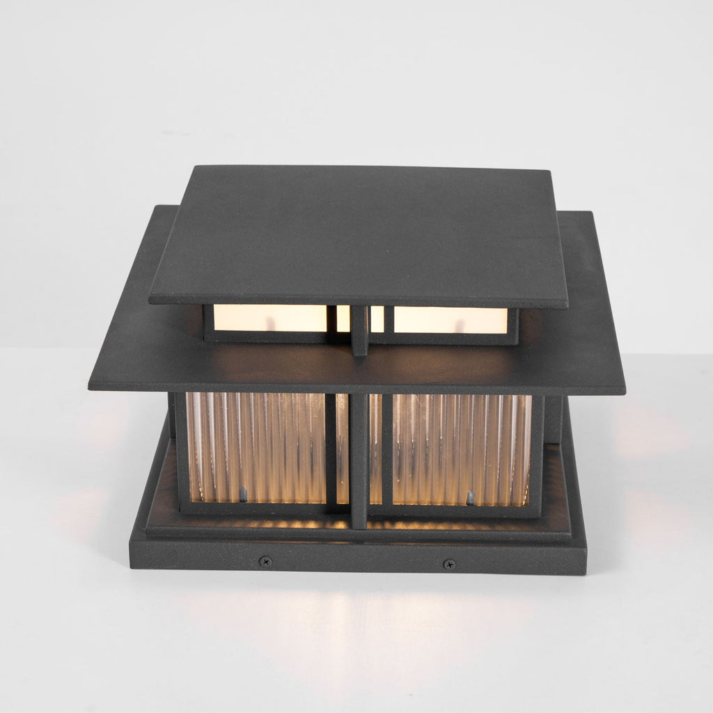 A front-on studio shot of this lit Clérachic pillar light, warm light glowing through its fluted glass panels.