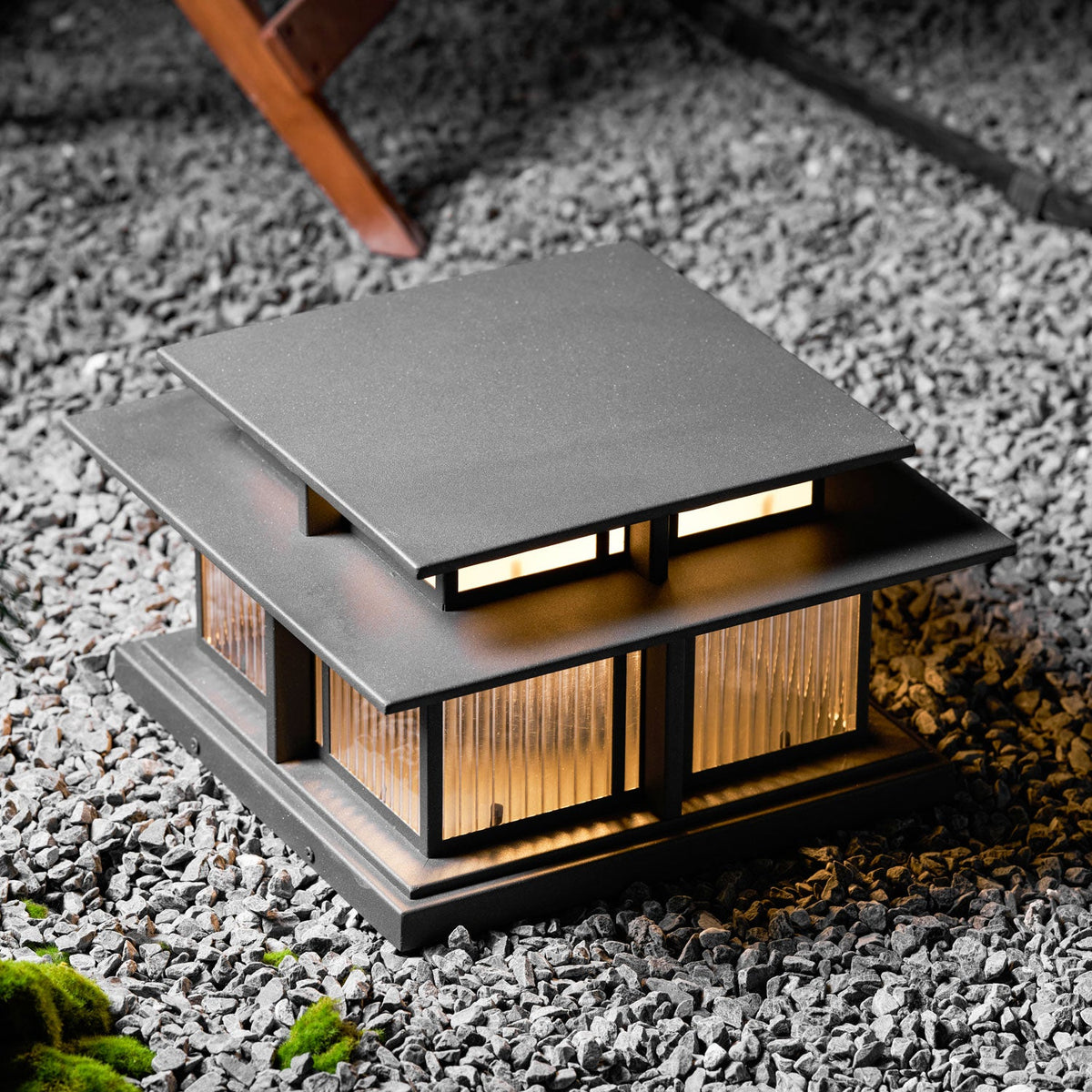 A closer view of this lit Clérachic pillar light on gravel landscaping, its frosted panels glowing warmly at night.