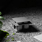Set among gravel and moss, this lit Clérachic pillar light glows quietly in a shaded garden corner.