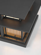 Close view of the layered aluminium roof and glowing top panel on this lit Clérachic pillar light.