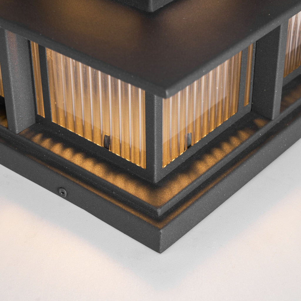 Close view of the base corner on this lit Clérachic pillar light, showing the fluted glass and a mounting screw.