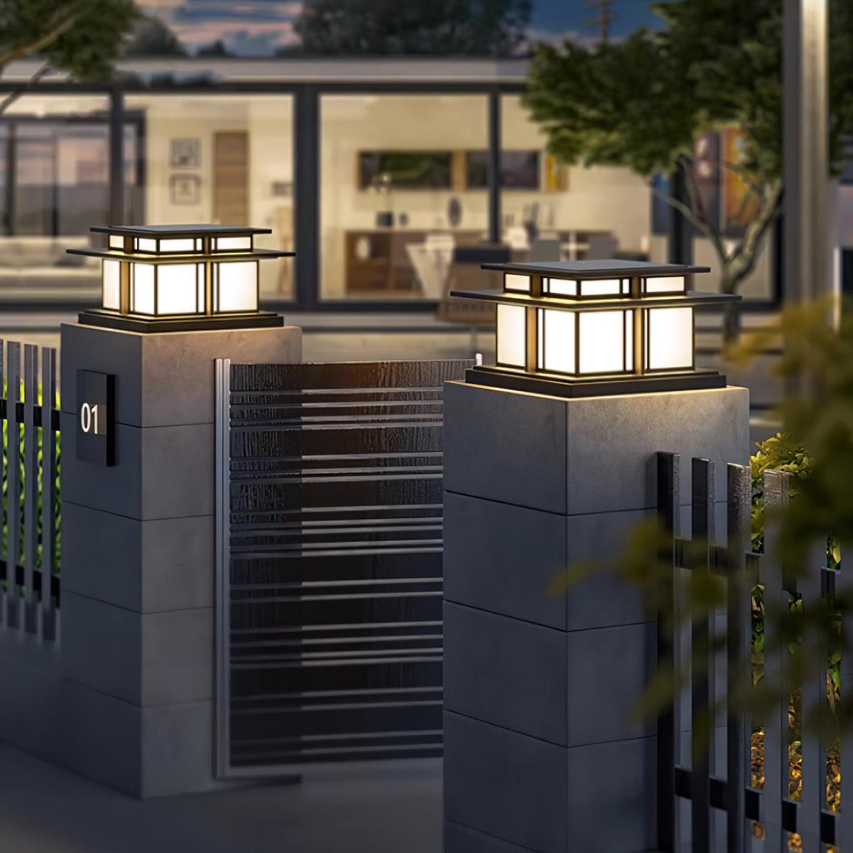 At a different angle, two lit Clérachic pillar lights sit above matching concrete gate posts by a metal gate.