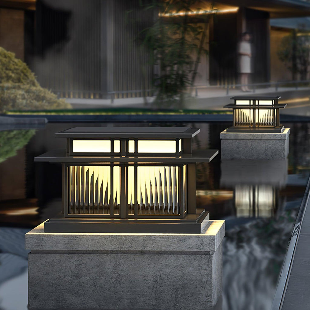 Fluted glass panels catch the light on this Clérachic pillar light, its reflection visible in the still water beside it.