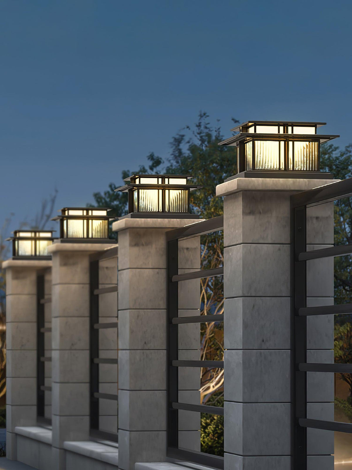 Under a deep blue evening sky, four lit Clérachic pillar lights line a row of concrete posts beside a metal fence.