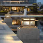 Two lit Clérachic pillar lights stand beside a reflecting pool at dusk, one on a raised stone plinth.