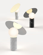 Two Clérachic tilting disc lamps rendered side by side on a plain background, comparing the white marble and black marble bases.