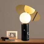 The Clérachic lamp glows on a wood table beside a framed photo and a stack of books, set against a warm brown wall.