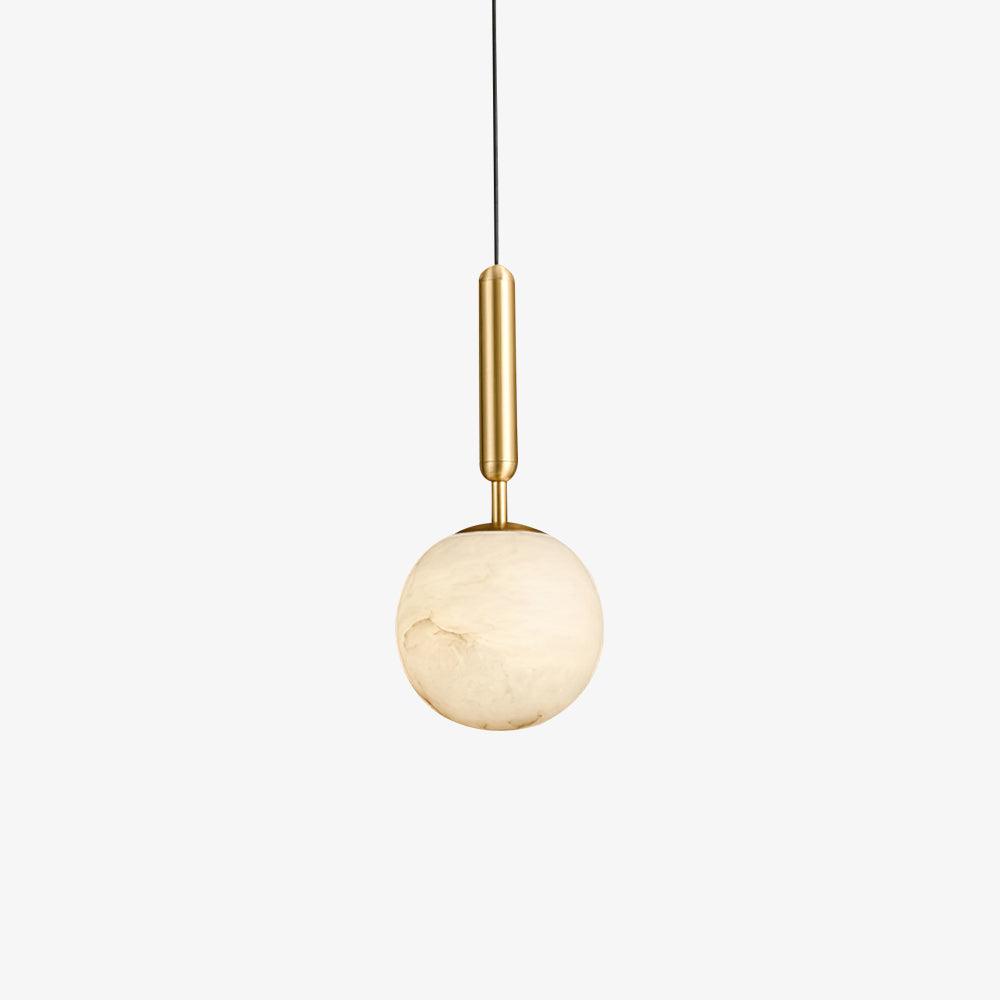 The pendant lit beside an upholstered headboard, an olive branch in a stone vase below.