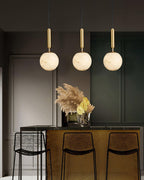 Three pendants hung at staggered heights above a black kitchen island with pampas grass.