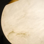 Extreme close-up of the alabaster globe and the brass cap where the stem meets the sphere.