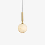 Studio view on white of the pendant, the brass stem catching light above the stone globe.