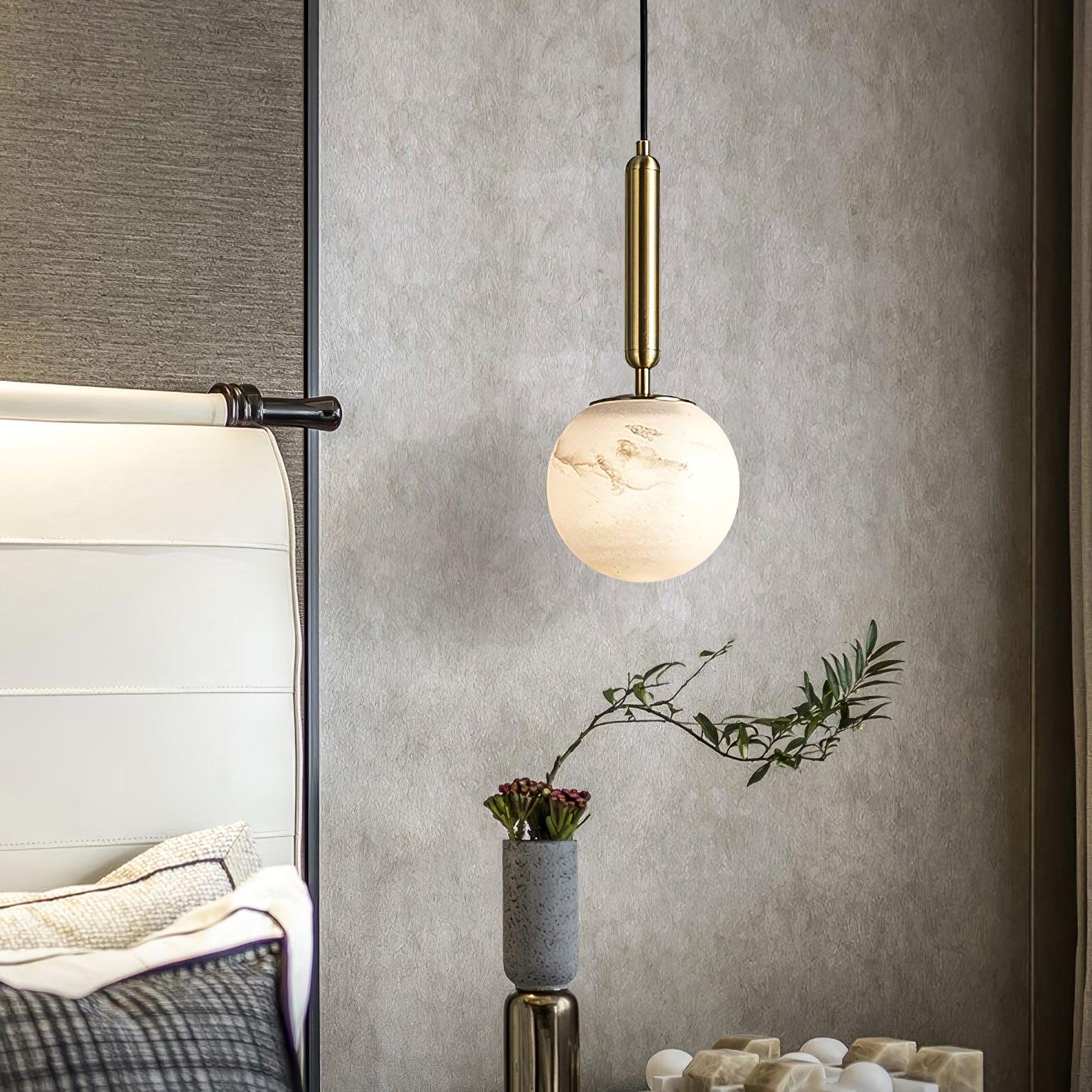 Lit against a dark grey panelled wall above a nightstand stacked with books.