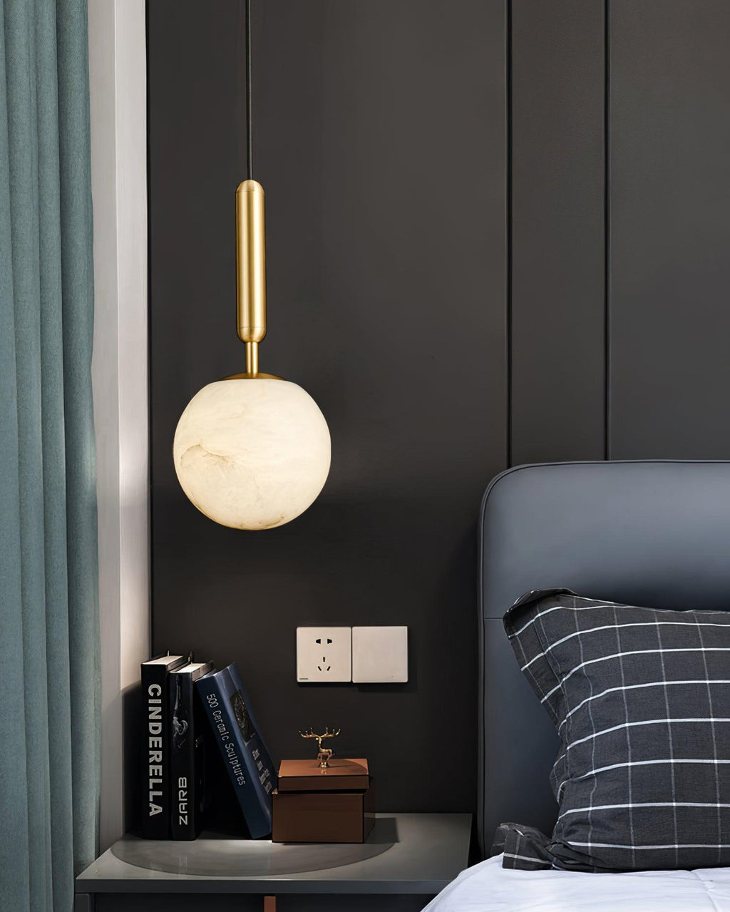 Two pendants photographed against black fabric, both alabaster globes lit warm.