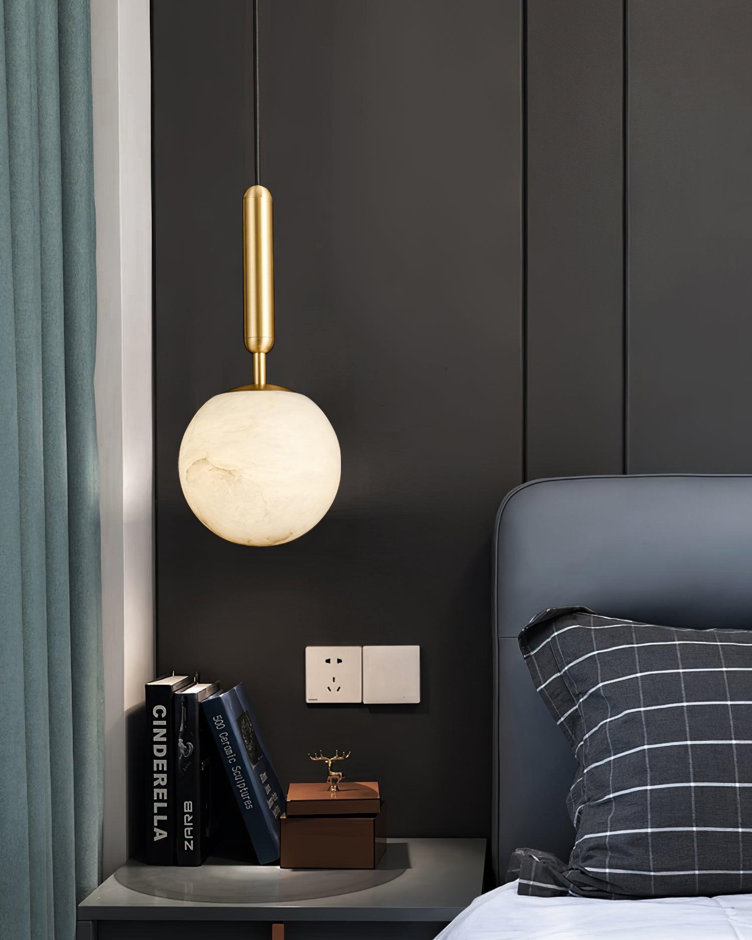 Two pendants photographed against black fabric, both alabaster globes lit warm.